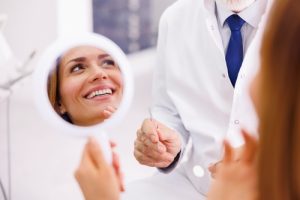 woman looking at her smile in hand mirror