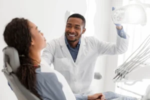 Male dentist in 48334, turning on equipment before check-up and greeting patient.
