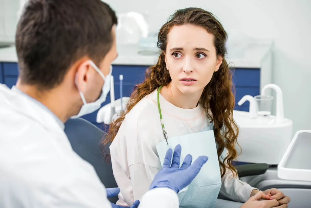 A worried looking patient is looking at an emergency dentist in Farmington Hills, MI