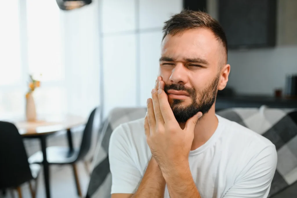 A young man suffering from toothache, in need of emergency dentist in Farmington Hills, MI
