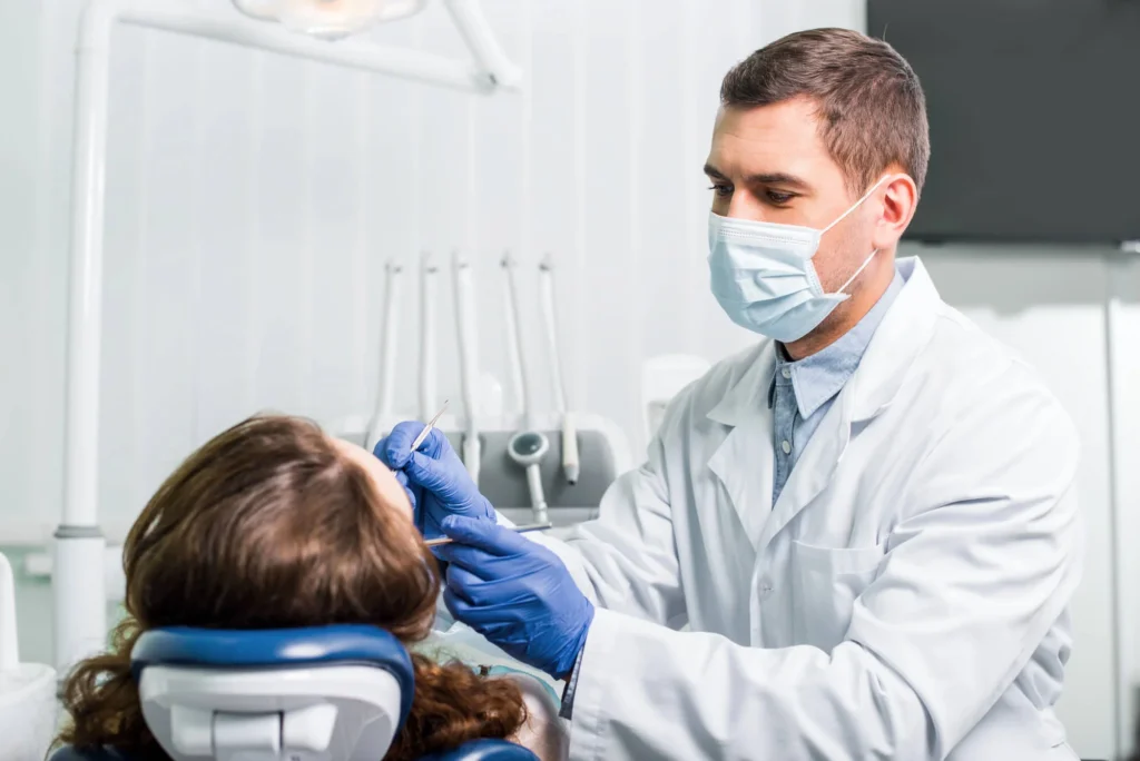 Emergency dentist in Farmington Hills, MI, wearing a mask, treating pacient